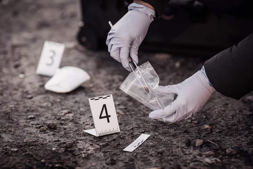 Image is of investigators collecting evidence at a crime scene, concept of a criminal defense lawyer reviewing forensic evidence in a criminal case