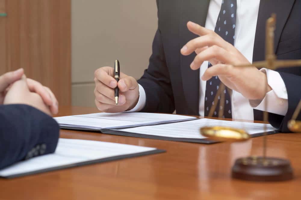 Image is of a lawyer discussing documents with a client at a desk, concept of a DUI lawyer providing legal guidance